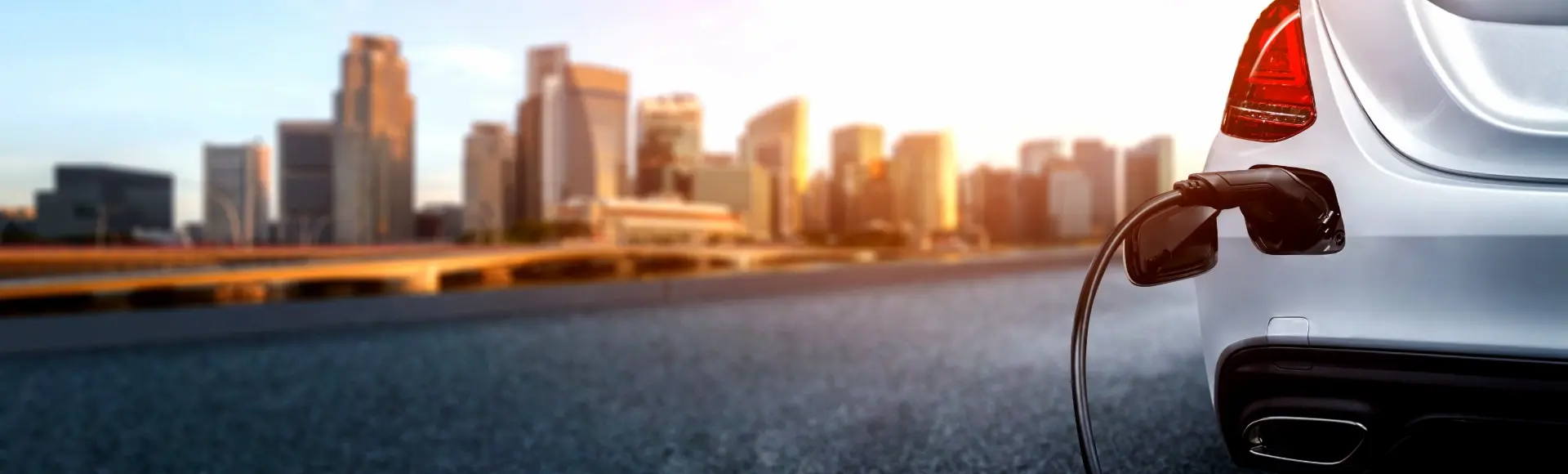 At dusk, an electric car is charging at the edge of the city.